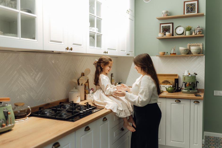 A mother and her daughter share a tender moment in a cozy, well-decorated kitchen setting.
