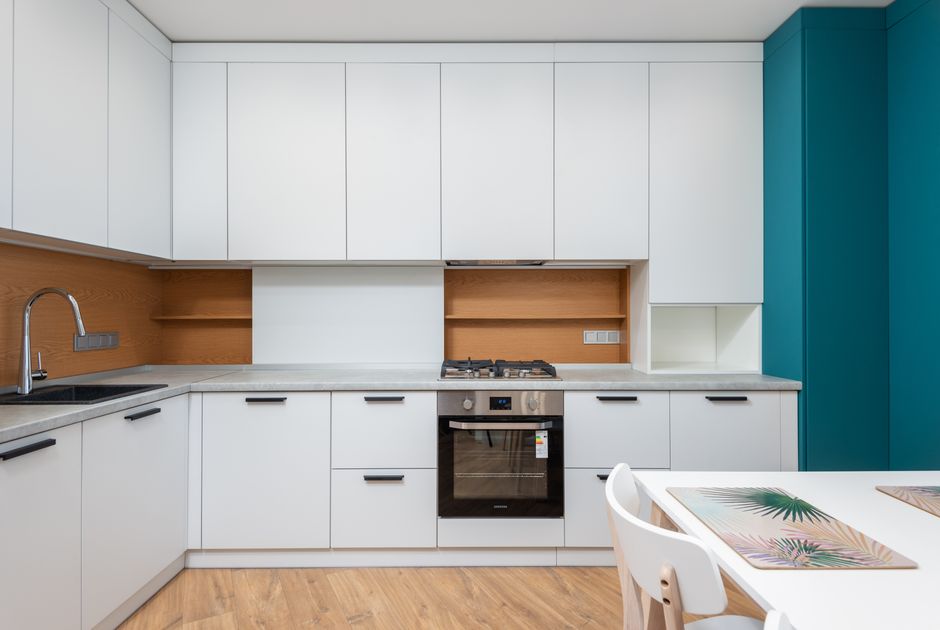 Contemporary kitchen interior with cabinets and gas stove above oven against table with placemats in house