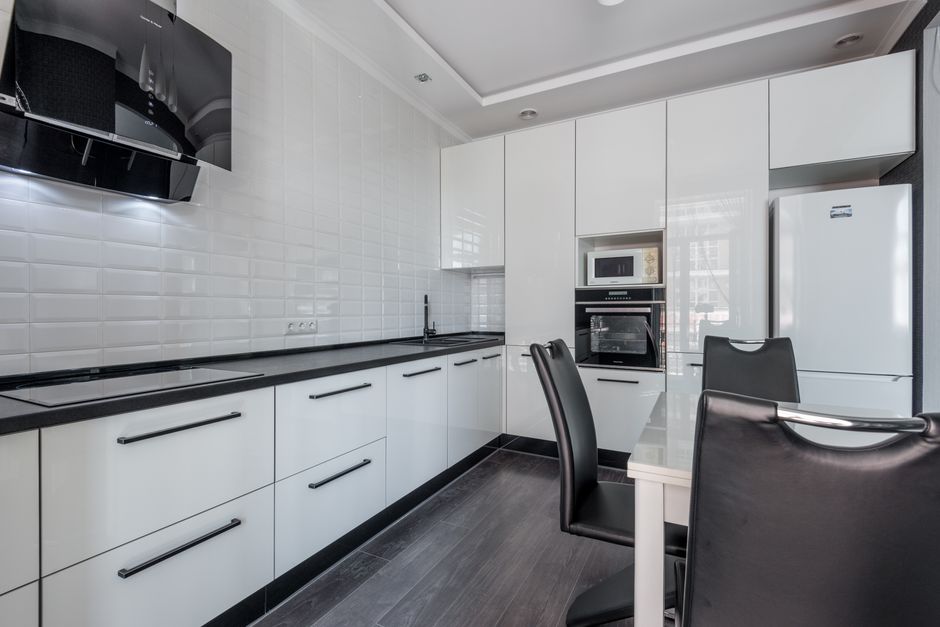 Sleek modern kitchen with white cabinets, black accents, and dining area.