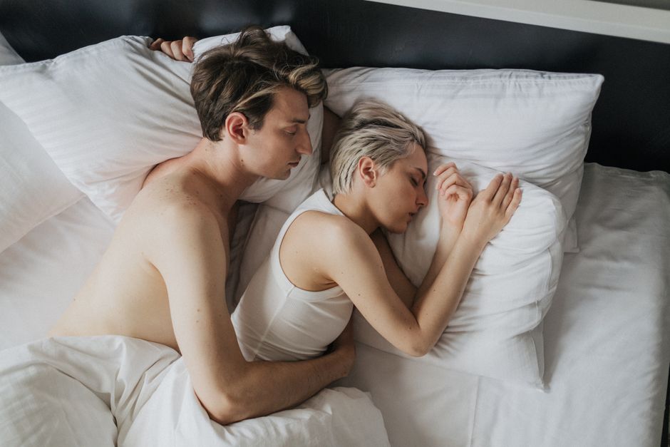 Couple embracing while sleeping peacefully in a cozy bedroom setting.