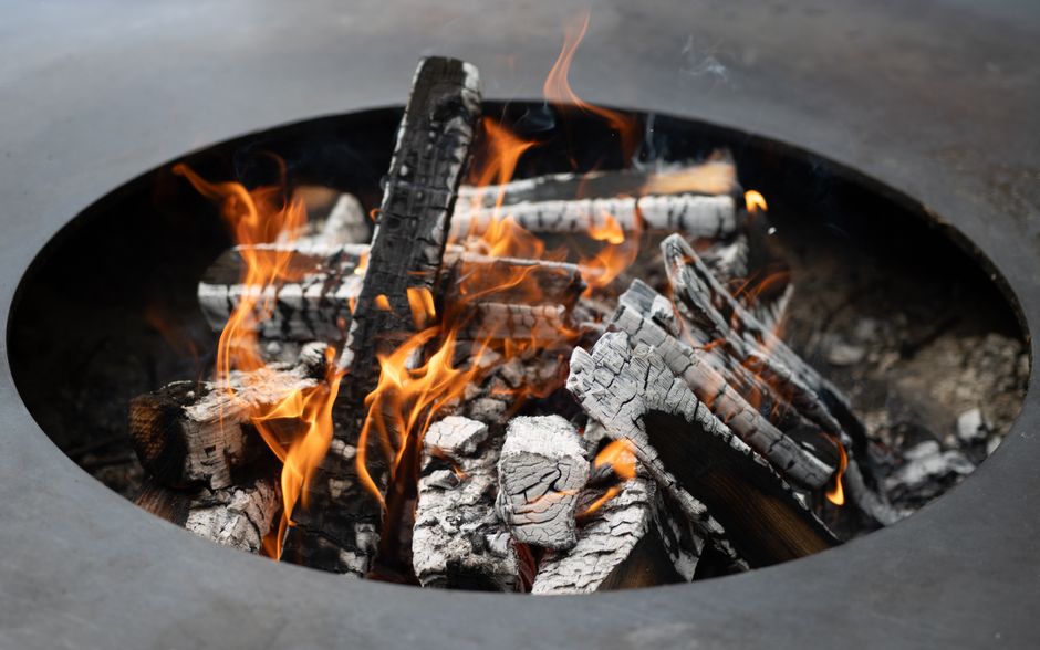 A close-up view of burning firewood with vibrant flames in a metal firepit.