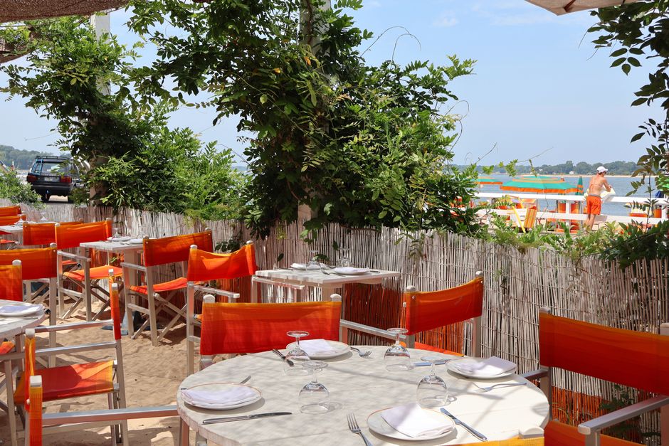 Charming outdoor dining area with orange chairs on Shelter Island beach.