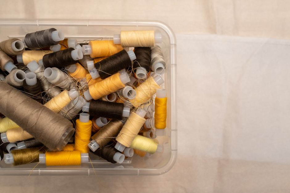 A bird's-eye view of various colored sewing threads neatly stored in a plastic box.