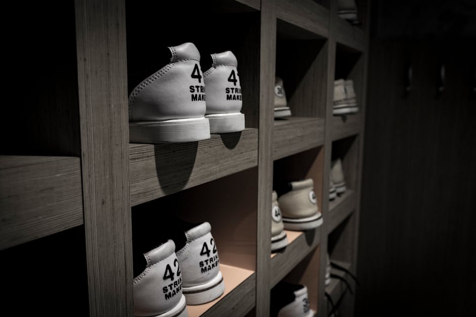 White sneakers labeled with '42' are neatly organized on wooden shelves in a dimly lit room.