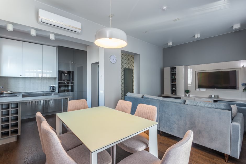 Spacious open-plan living area with modern furnishings, featuring a dining table, sofa, and kitchen.