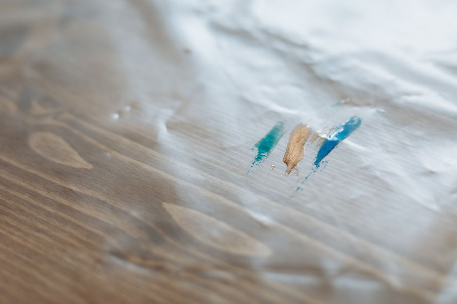 Detailed view of colorful paint streaks on a wooden surface covered in plastic.