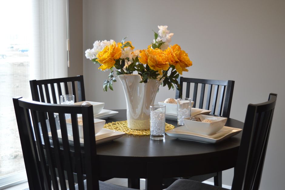 A stylish dining area featuring a round table with vibrant floral centerpiece and modern tableware.