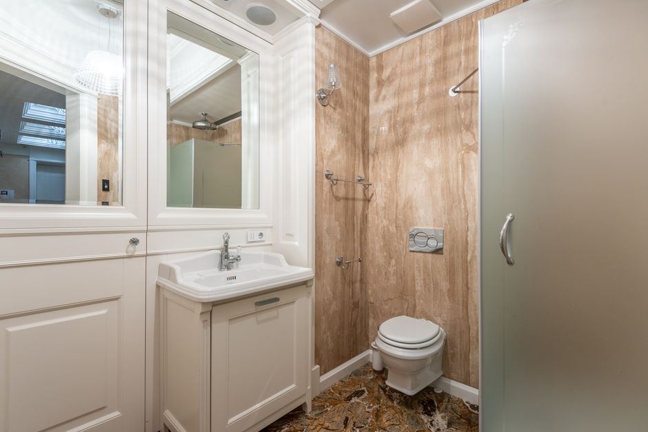Luxurious bathroom with minimalist design, featuring white cabinets and marble accents.
