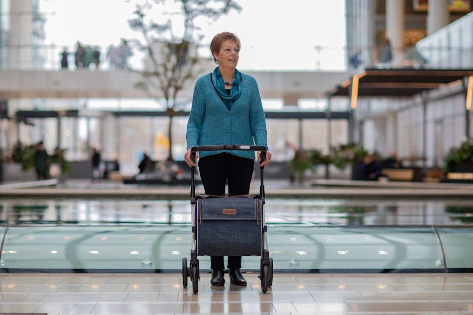 A senior woman using a rollator walker inside a modern shopping mall.