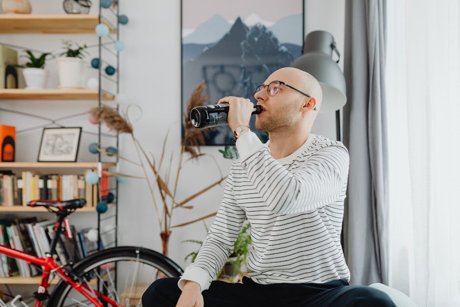 Bald man relaxing and drinking a beverage in a cozy living room.