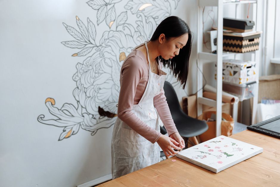 An artist designs floral art on canvas in a cozy studio setting.